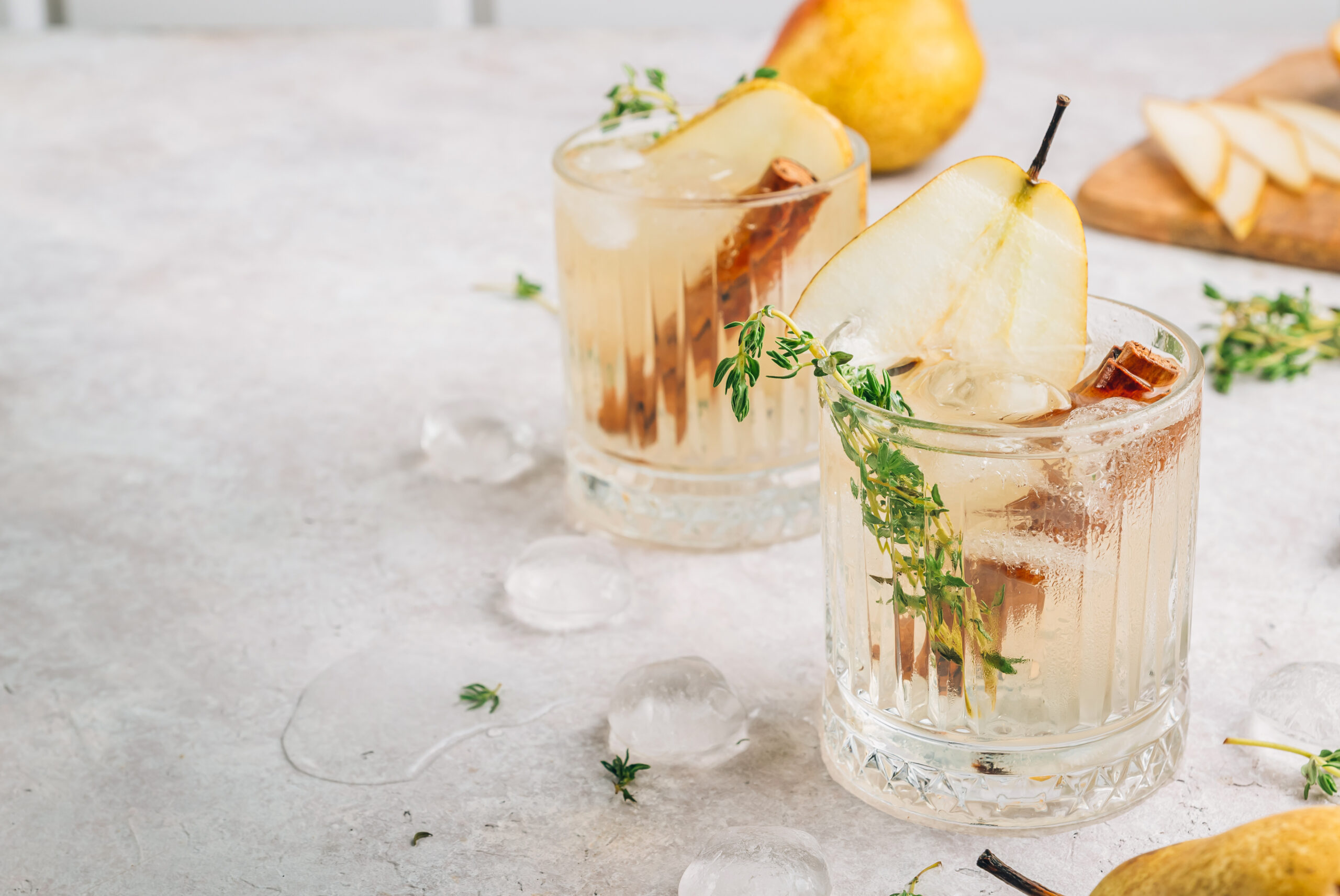 Festive summer spicy cocktail with pears and thyme on light beige background. Selective focus with copy space